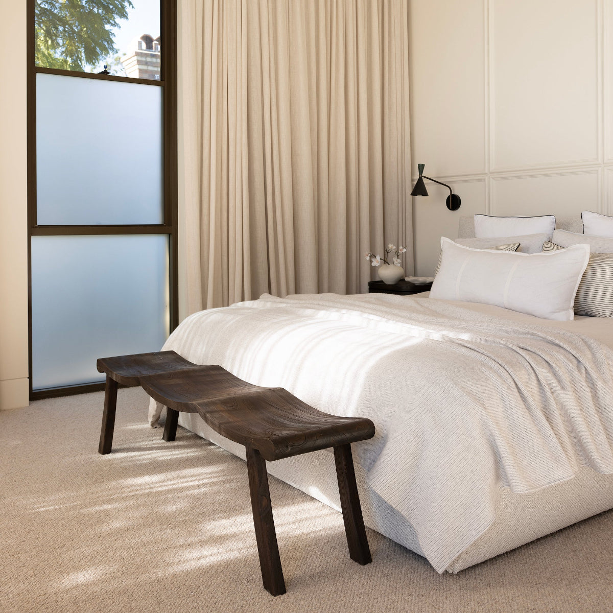 Modern bedroom with a bed, bench, and large window.